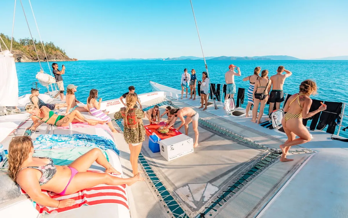 Travellers stretched out on the deck of a sailing yacht at anchor in the Whitsundays