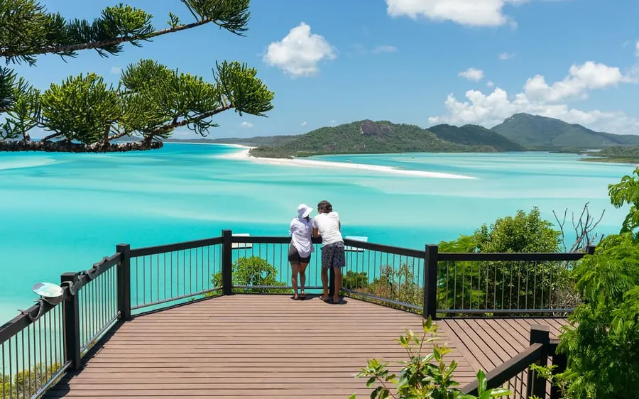 两名游客在 Hill Inlet 观景台俯瞰 Whitehaven Beach 回旋的沙纹